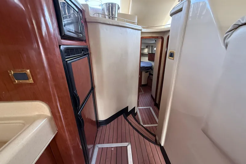 Slide: The Image of Interior view of 2001 Sea Ray 450 Express Bridge yacht, featuring wood paneling and compact kitchen area. - 22