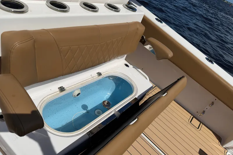 Slide: The Image of 2021 Fountain 38 CC LS boat interior with tan seating and livewell, ocean in background. - 12