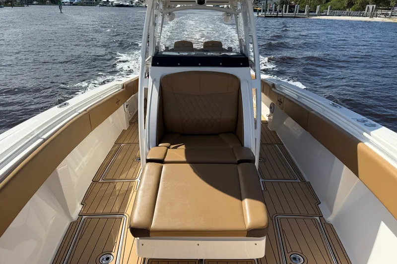 Slide: The Image of 2021 Fountain 38 CC LS boat with tan seating and wooden deck on water. - 9