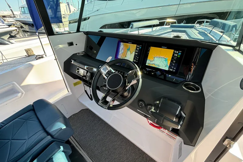 Slide: The Image of 2024 Axopar 29 XC Cross Cabin helm with modern navigation displays and steering wheel. - 16