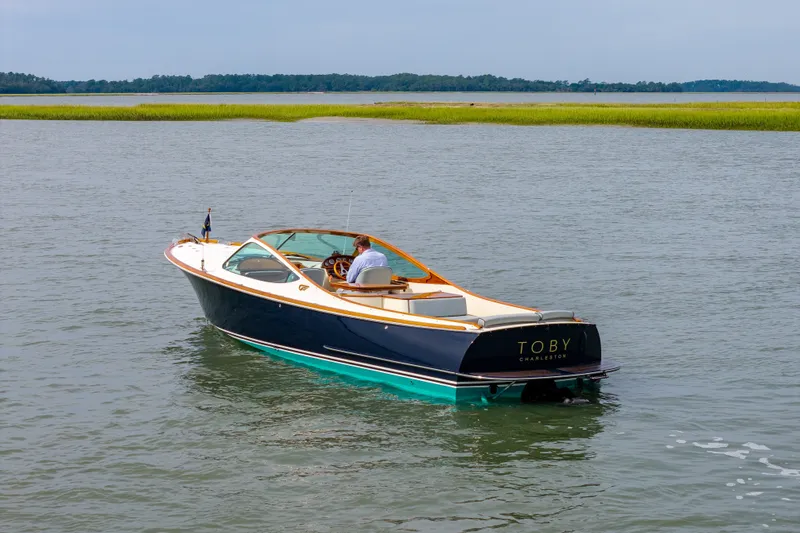 Slide: The Image of 2007 Hinckley Talaria 29R boat cruising on calm water near grassy shoreline. - 18