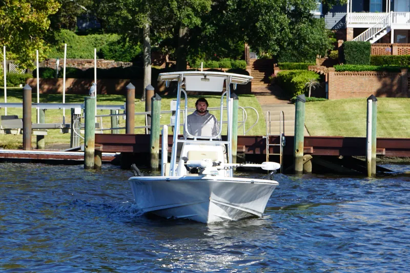Slide: The Image of 2017 Sportsman Tournament 214 Bay Boat cruising near a dock with lush greenery. - 17