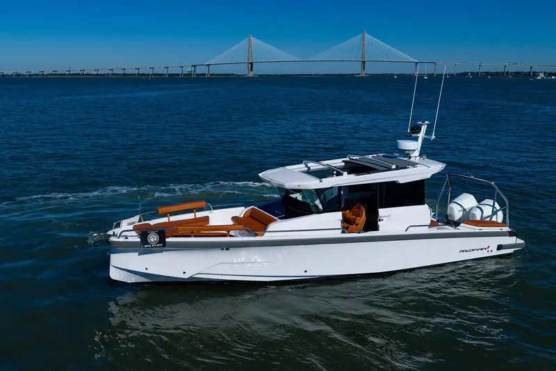 The Image of 2026 Axopar 29 XC Cross Cabin boat cruising near a bridge on a sunny day. - 3