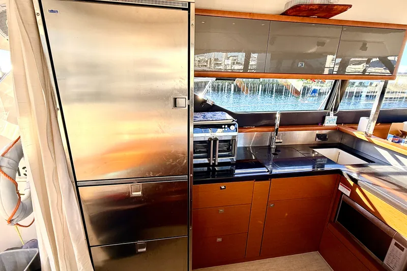 Slide: The Image of Modern kitchen interior on a 2014 Prestige 620 yacht, featuring stainless steel appliances and sleek cabinetry. - 23
