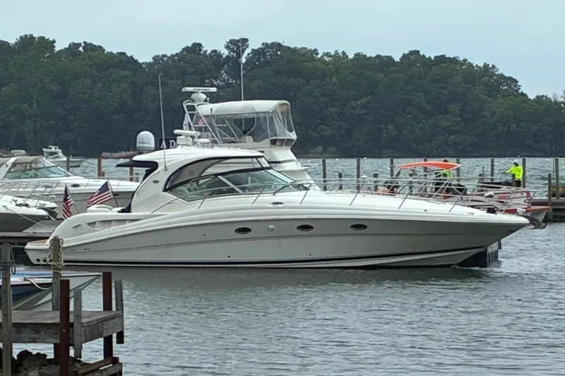 The Image of 2005 Sea Ray 420 Sundancer yacht docked at a marina with lush green trees. - 0