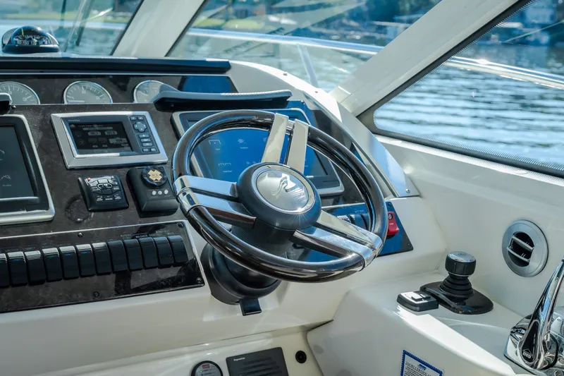 Slide: The Image of Cockpit of 2012 Sea Ray 450 Sundancer with steering wheel and control panel. - 24
