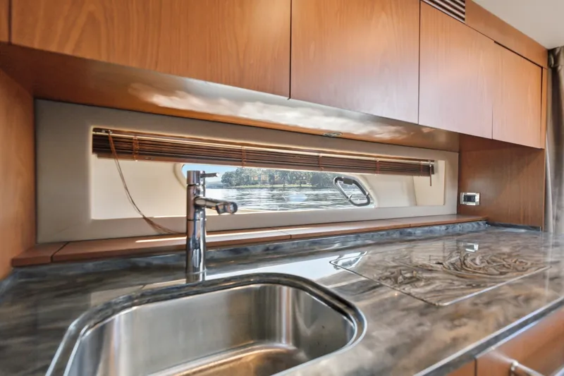 Slide: The Image of Luxurious kitchen interior of 2012 Sea Ray 450 Sundancer yacht with sleek countertop and window view. - 42