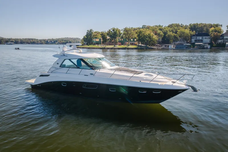 Slide: The Image of 2012 Sea Ray 450 Sundancer yacht on a serene lake with lush shoreline. - 4