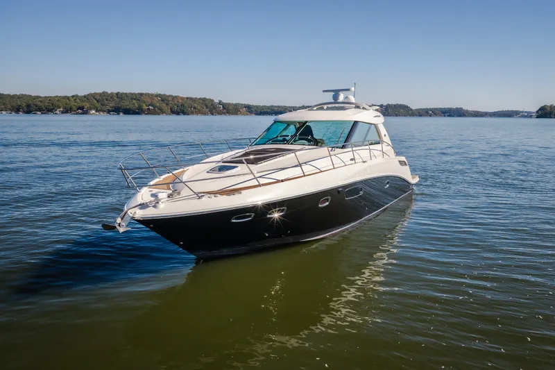 Slide: The Image of 2012 Sea Ray 450 Sundancer yacht cruising on a serene lake under clear skies. - 6