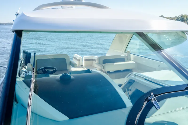 Slide: The Image of 2012 Sea Ray 450 Sundancer cockpit with steering wheel and seating, overlooking calm waters. - 52