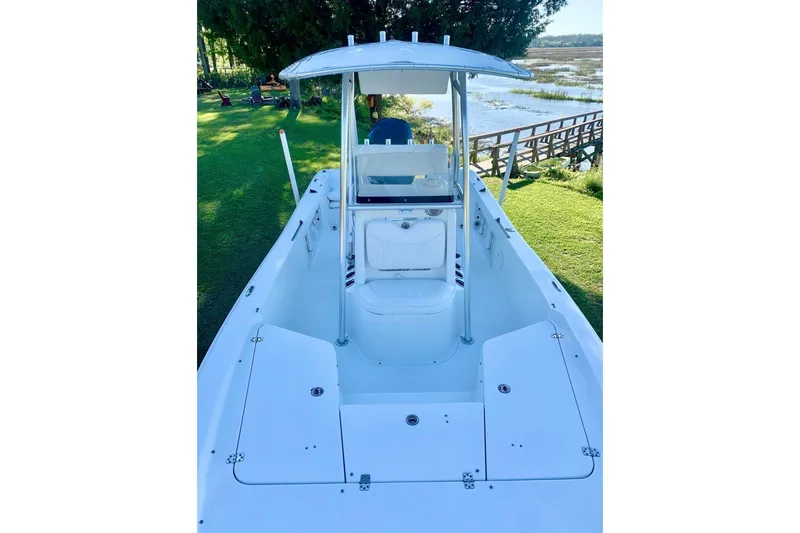 Slide: The Image of 2012 Sea Hunt BX22 Pro boat with T-top, docked near grassy shoreline. - 11