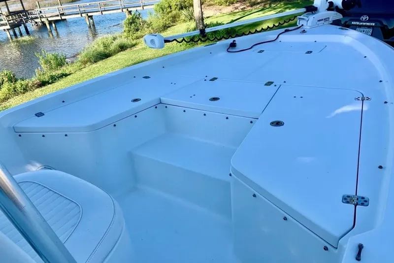 Slide: The Image of 2012 Sea Hunt BX22 Pro boat deck with storage compartments, near a scenic waterfront. - 12