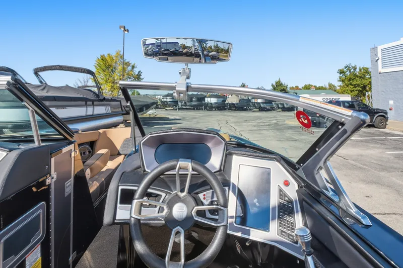 Slide: The Image of 2020 MasterCraft X24 boat dashboard with steering wheel and control panel in a parking lot. - 29