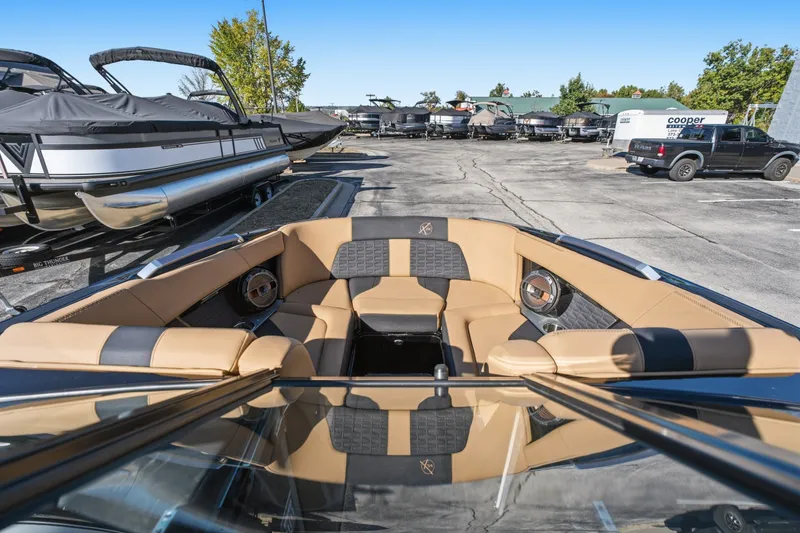 Slide: The Image of 2020 MasterCraft X24 boat interior with tan and black seating in a marina setting. - 30