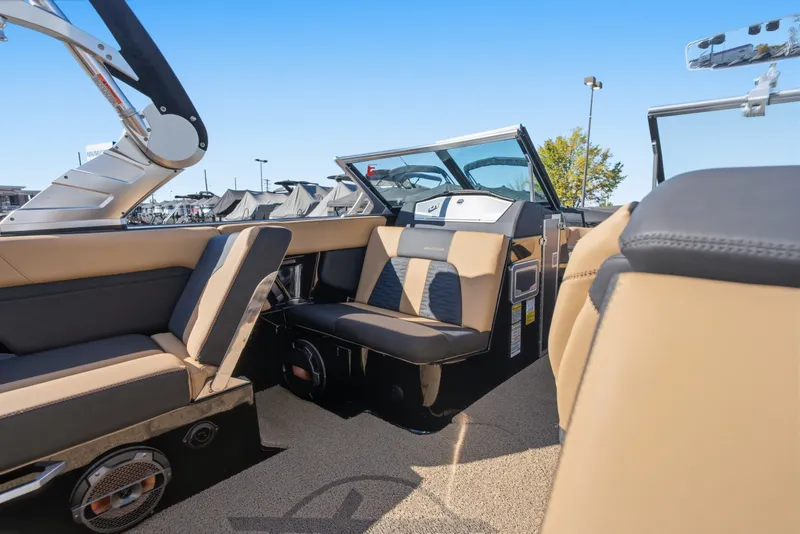 Slide: The Image of 2020 MasterCraft X24 boat interior with tan and black seating, under clear blue sky. - 24