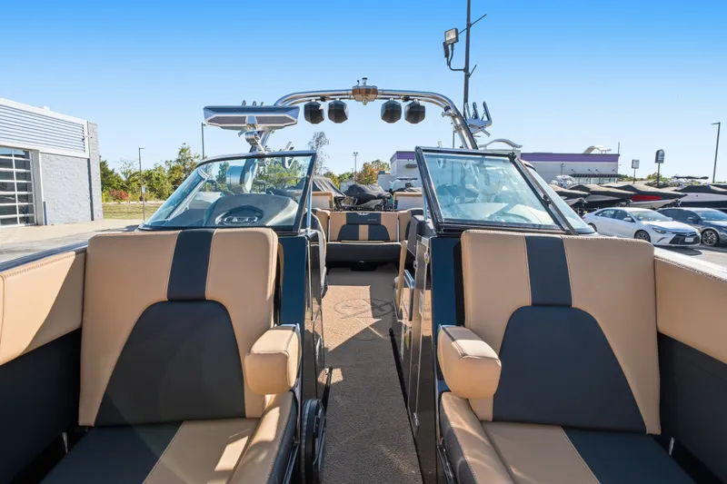 Slide: The Image of 2020 MasterCraft X24 boat interior with tan and black seating, parked outdoors. - 34