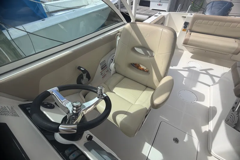 Slide: The Image of 2019 Sailfish 245 DC boat interior with steering wheel and beige seating. - 44