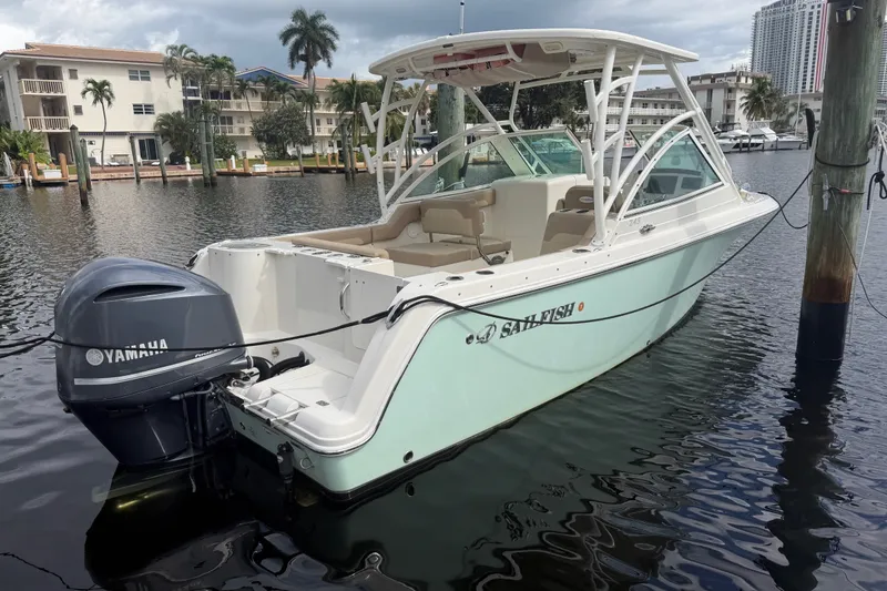Slide: The Image of 2019 Sailfish 245 DC boat docked with Yamaha engine, surrounded by waterfront buildings. - 2