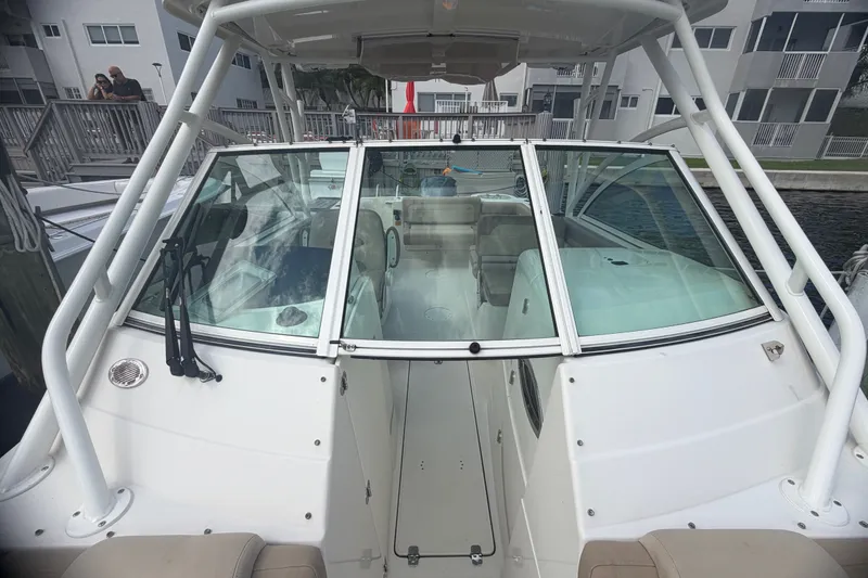 Slide: The Image of 2019 Sailfish 245 DC boat with spacious seating and clear windshield, docked near waterfront buildings. - 40