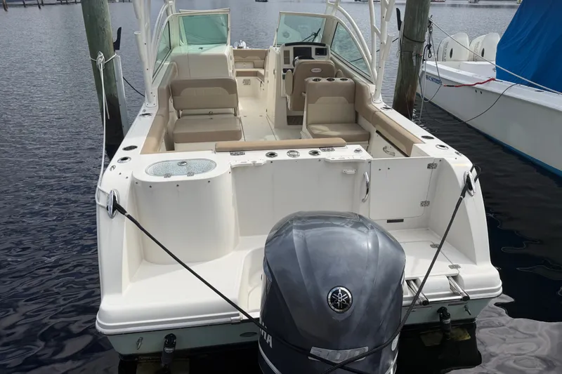 Slide: The Image of 2019 Sailfish 245 DC boat docked, featuring spacious seating and outboard motor. - 5
