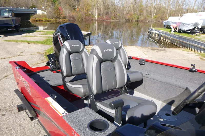 Slide: The Image of 2022 Lund 1650 Angler SS boat with dual seats, docked near a calm lake. - 11