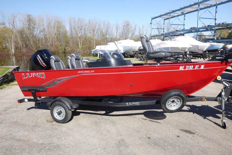 The Image of Red 2022 Lund 1650 Angler SS fishing boat on trailer, parked outdoors. - 0