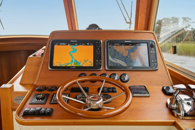 Slide: The Image of Hinckley Talaria 44 Flybridge 2002 helm with dual navigation screens and wooden steering wheel. - 21