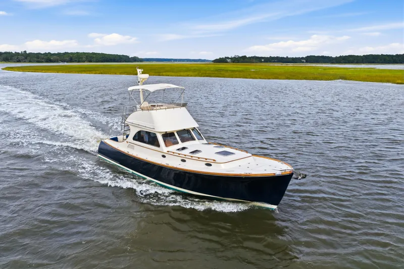 Slide: The Image of Hinckley Talaria 44 Flybridge 2002 cruising on a scenic waterway with lush green shoreline. - 45