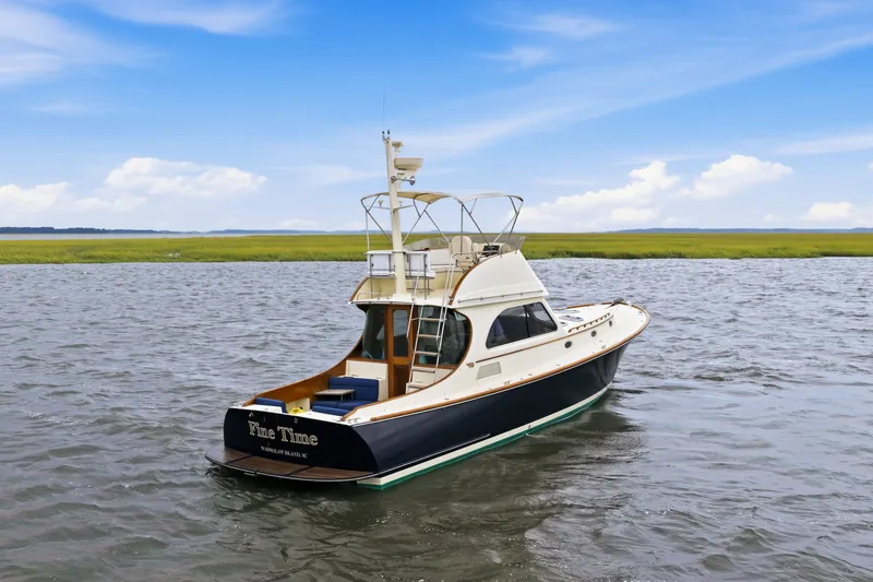 Slide: The Image of 2002 Hinckley Talaria 44 Flybridge yacht on calm water under blue sky. - 4