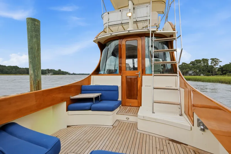 Slide: The Image of 2002 Hinckley Talaria 44 Flybridge yacht with blue seating and wooden accents on deck. - 2