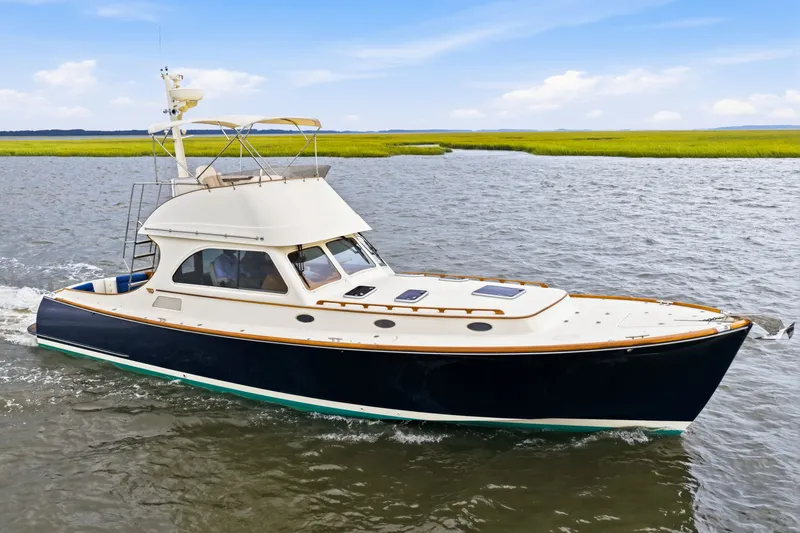 Slide: The Image of 2002 Hinckley Talaria 44 Flybridge cruising on open water under a clear blue sky. - 46