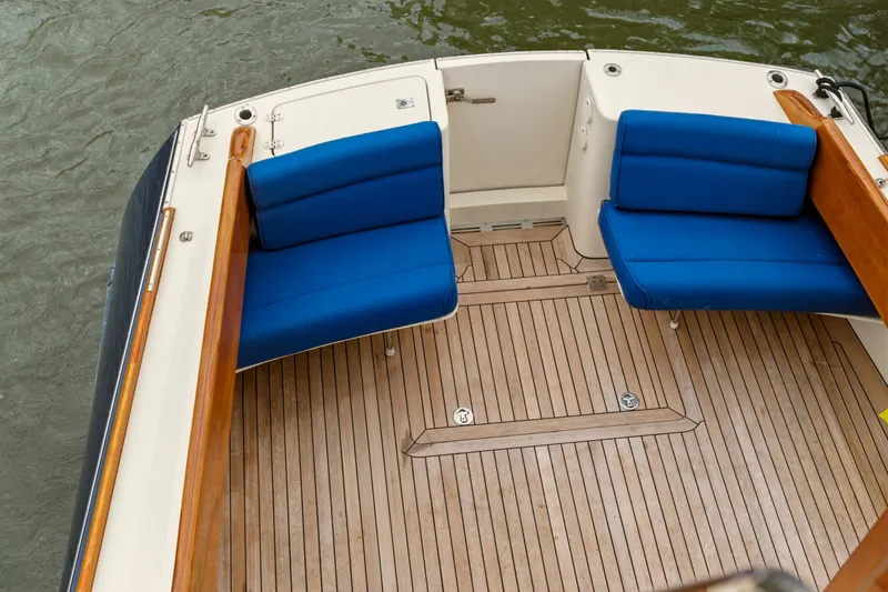 Slide: The Image of Hinckley Talaria 44 Flybridge 2002, teak deck with blue cushioned seating, docked on water. - 6