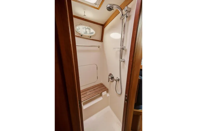 Slide: The Image of Shower area in 2002 Hinckley Talaria 44 Flybridge yacht with wooden bench and porthole. - 38