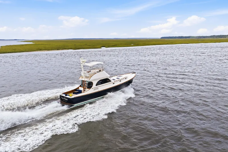 Slide: The Image of Hinckley Talaria 44 Flybridge 2002 cruising on open water, scenic coastal background. - 44
