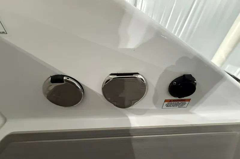 Slide: The Image of 2025 Monterey Elite 27 OB boat fuel and power outlets with safety warning label. - 16