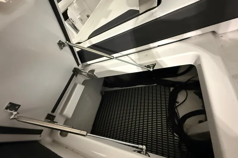 Slide: The Image of Open storage compartment in 2025 Monterey Elite 27 OB boat, featuring hydraulic hinges and black mat. - 48