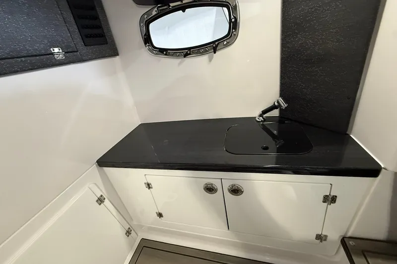 Slide: The Image of 2025 Monterey Elite 27 OB boat interior with sleek black countertop and compact sink. - 40