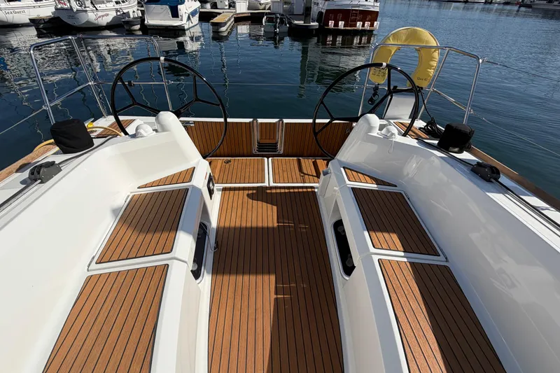 Slide: The Image of 2024 Jeanneau Sun Odyssey 349 sailboat cockpit with dual steering wheels and teak flooring. - 26