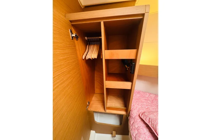 Slide: The Image of Wooden closet interior on 2024 Jeanneau Sun Odyssey 349 yacht, featuring hangers and shelves. - 66