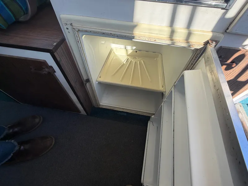 Slide: The Image of An open fridge inside a boat, featuring an empty shelf and a door compartment. - 31
