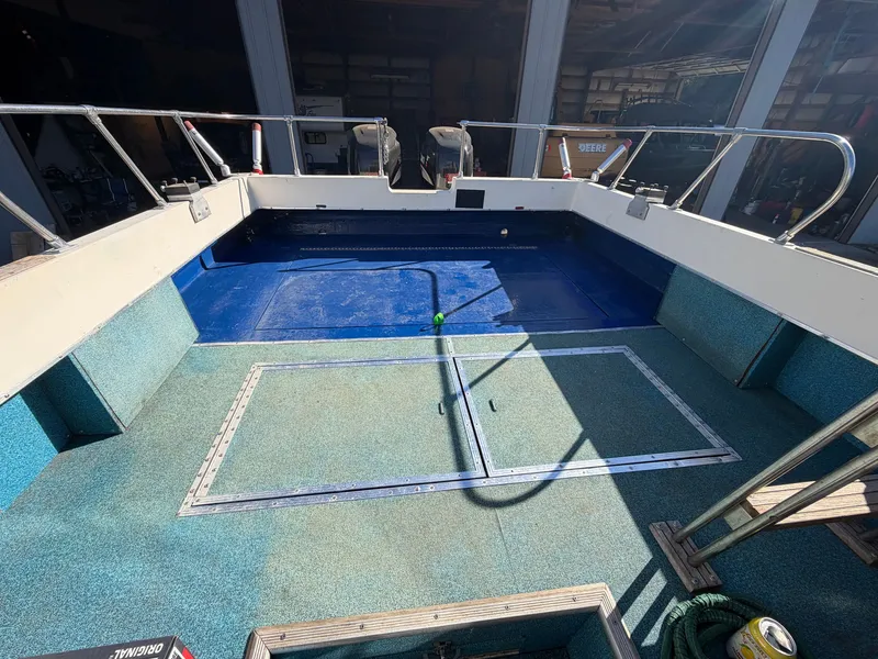 Slide: The Image of The image shows the spacious deck of a 1974 Fiberform Sportfisher 31 with blue and green flooring. - 14