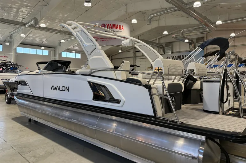 Slide: The Image of 2027 Avalon 2585 EXCALIBUR QLWS pontoon boat displayed in a showroom. - 2