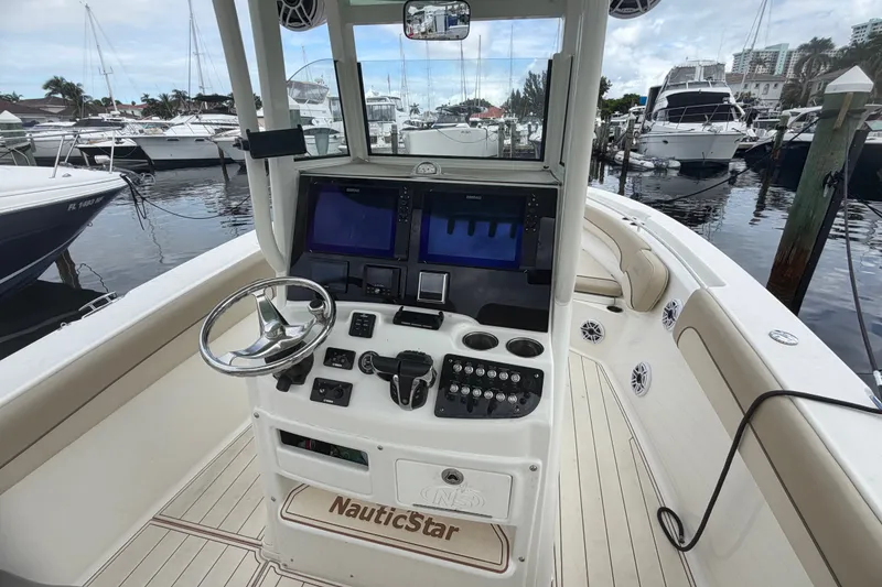 Slide: The Image of 2022 NauticStar 28 XS boat dashboard with steering wheel and navigation screens at marina. - 49