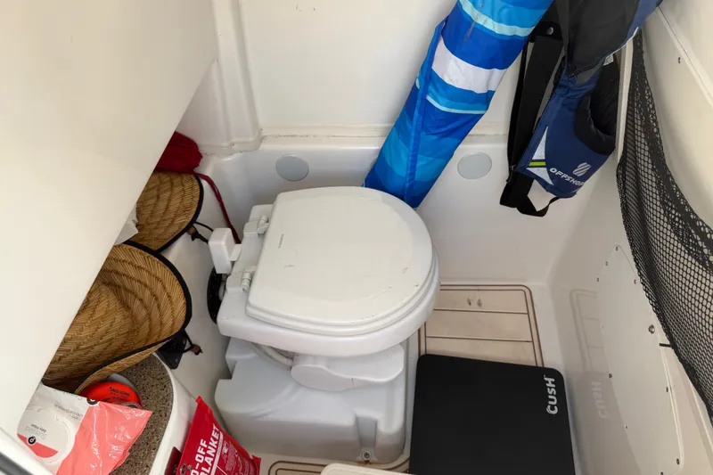 Slide: The Image of Interior of 2022 NauticStar 28 XS boat featuring a compact marine toilet. - 58