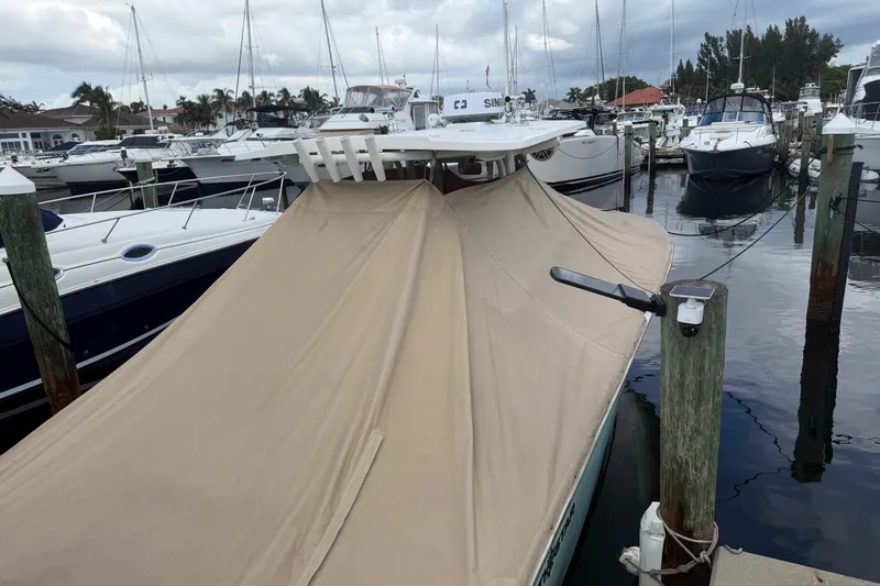 The Image of 2022 NauticStar 28 XS boat covered at marina, surrounded by other docked boats. - 0