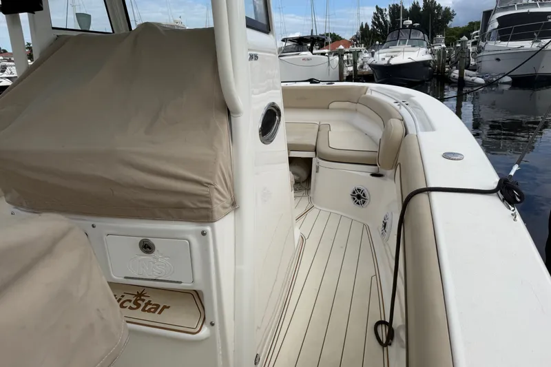 Slide: The Image of 2022 NauticStar 28 XS boat interior with seating and covered console at marina. - 14