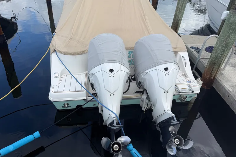 Slide: The Image of 2022 NauticStar 28 XS boat with twin outboard motors docked, covered with a beige tarp. - 1