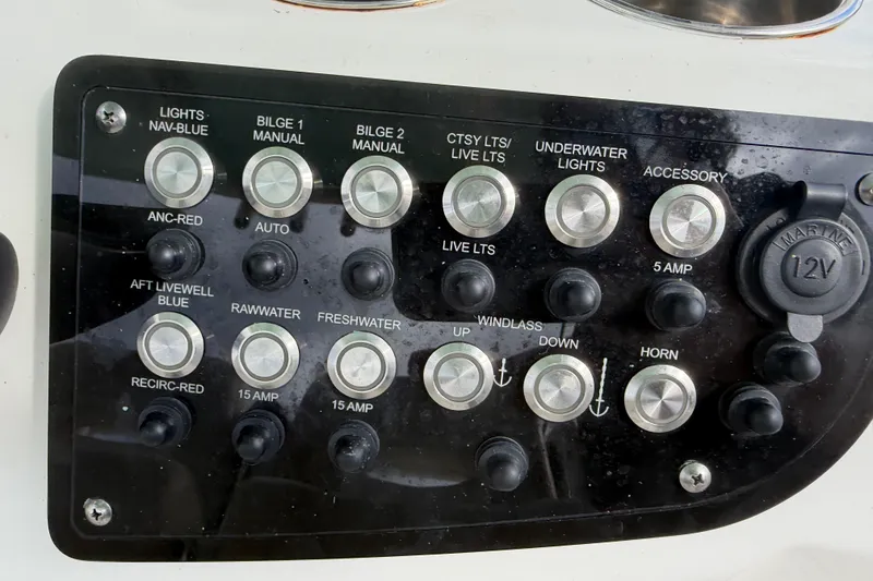 Slide: The Image of Control panel of a 2022 NauticStar 28 XS boat with various switches and buttons. - 35
