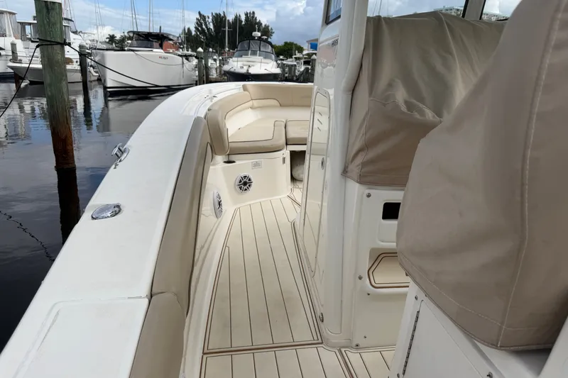 Slide: The Image of 2022 NauticStar 28 XS boat interior with beige seating and wood-like flooring at a marina. - 13