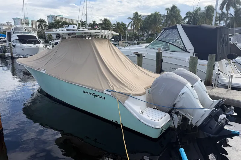 Slide: The Image of 2022 NauticStar 28 XS boat docked, covered, with twin Yamaha engines, in a marina setting. - 2